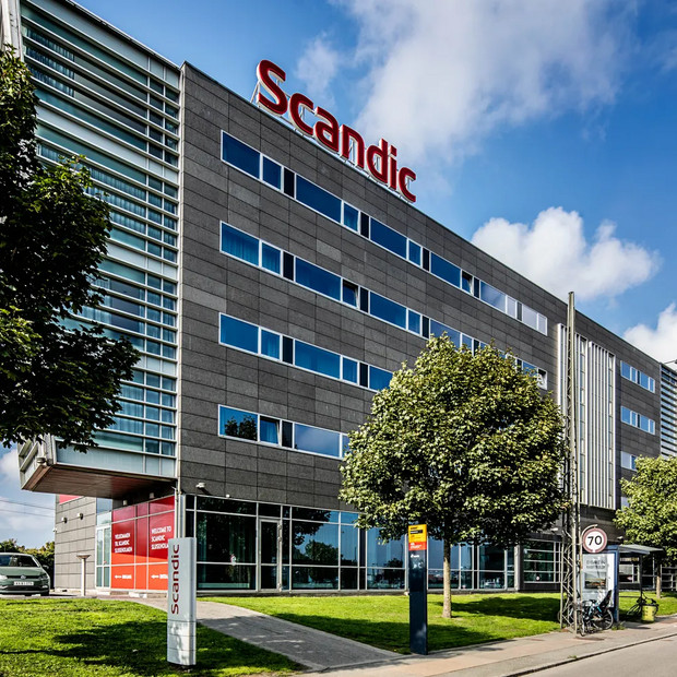 Large hotel building with the Scandic logo on top and green trees in front