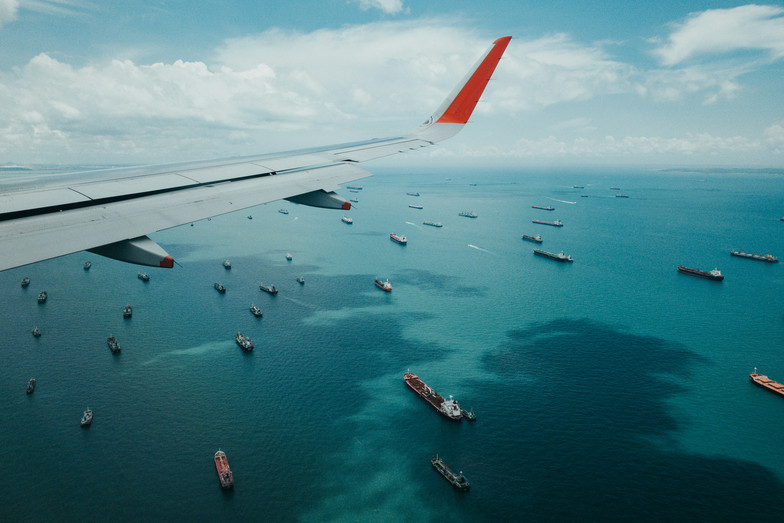 Shipping containers seen in the ocean under the wing of a plane