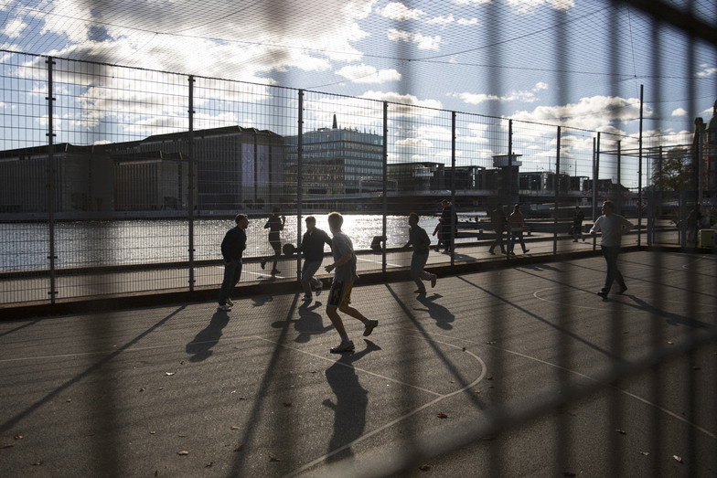 En gruppe mennesker, der spiller fodbold i en udendørs indhegning
